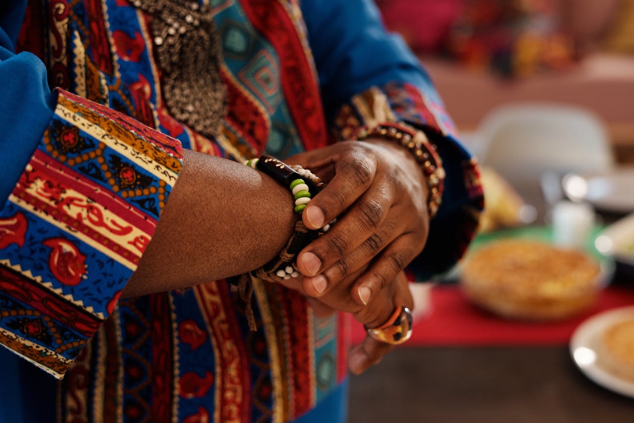 Close-up of hands adorned with a traditional bracelet and vibrant fabric, showcasing cultural style.